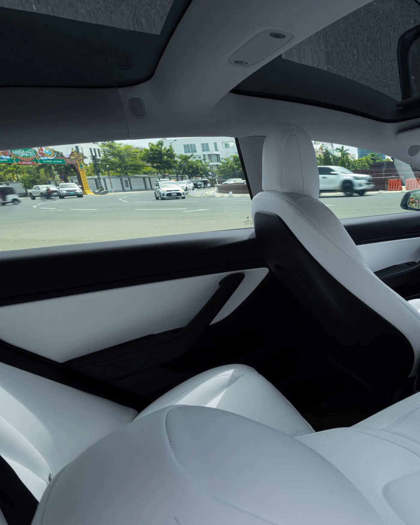 A bright car interior with white seats and a wide screen